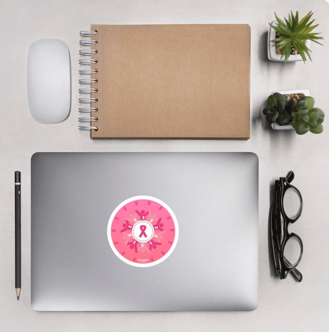 Aerial view of laptop showing pink circular design with breast cancer awareness symbols, laptop background is a desk with accessories