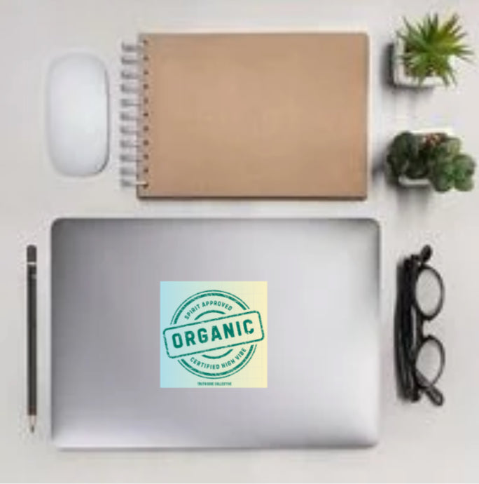 Laptop with a 'Certified Organic' square sticker on a desk with a notebook, mouse, and glasses.