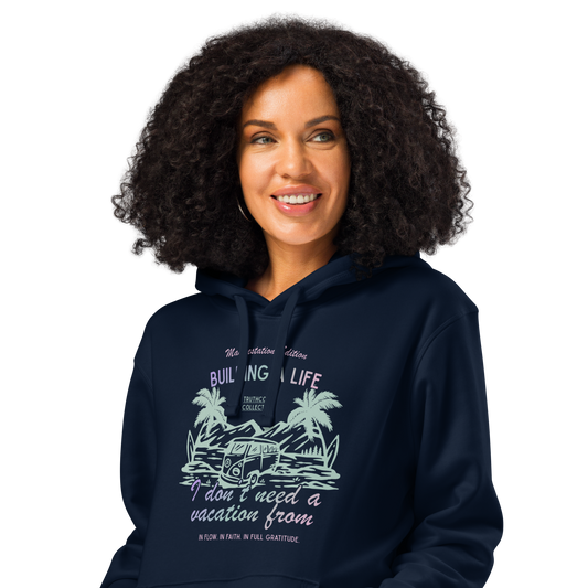 Woman wearing navy blue organic hoodie with beach style graphic design and text 'Building a life I don't need to run away from' on a white background
