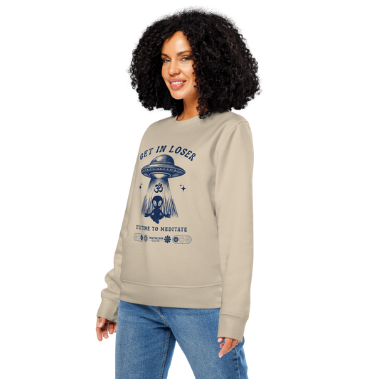 Woman wearing beige organic sweatshirt with alien and spaceship graphic and text 'Get in loser, it's time to meditate' on a white background