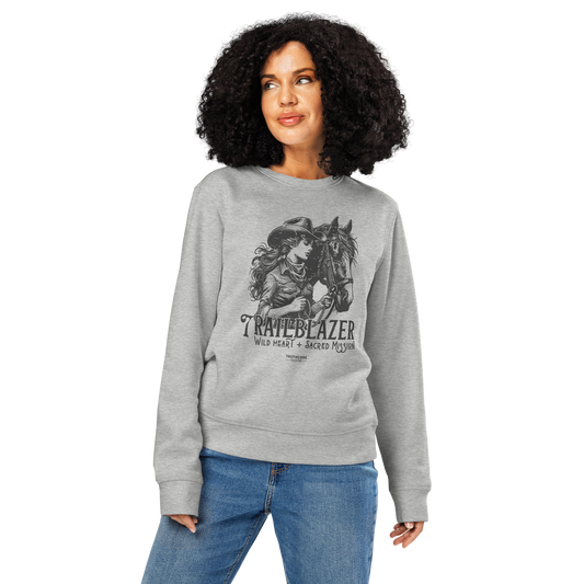 Woman wearing gray organic sweatshirt with graphic of a woman holding a horse and text 'Trailblazer' and 'Wild heart, sacred mission' on a white background