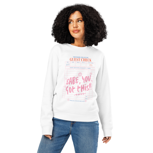 Woman wearing white organic sweatshirt with text 'Babe, you got this!' written on a guest check graphic design, sweatshirt on a white background