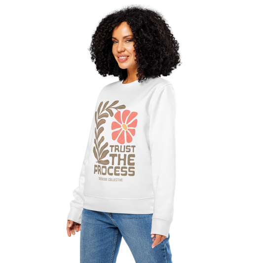 Woman wearing white organic sweatshirt with floral design and 'Trust The Process' text on a white background