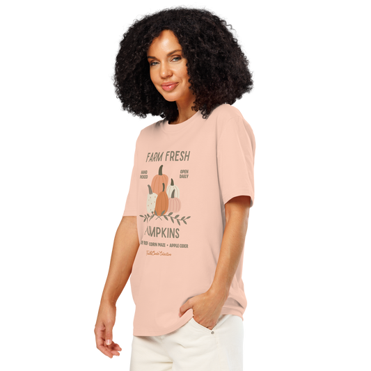Woman wearing peach organic t-shirt with pumpkin graphic and text 'Farm fresh pumpkins, hay rides, corn maze, apple cider' on a white background