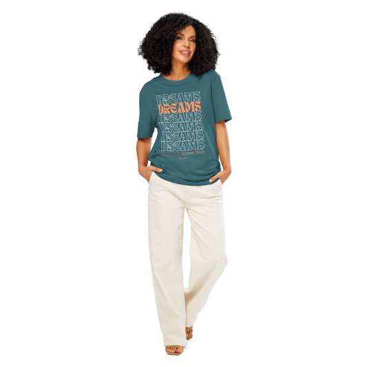 Woman wearing a teal organic t-shirt with text 'Dreams come true' and white pants on a white background