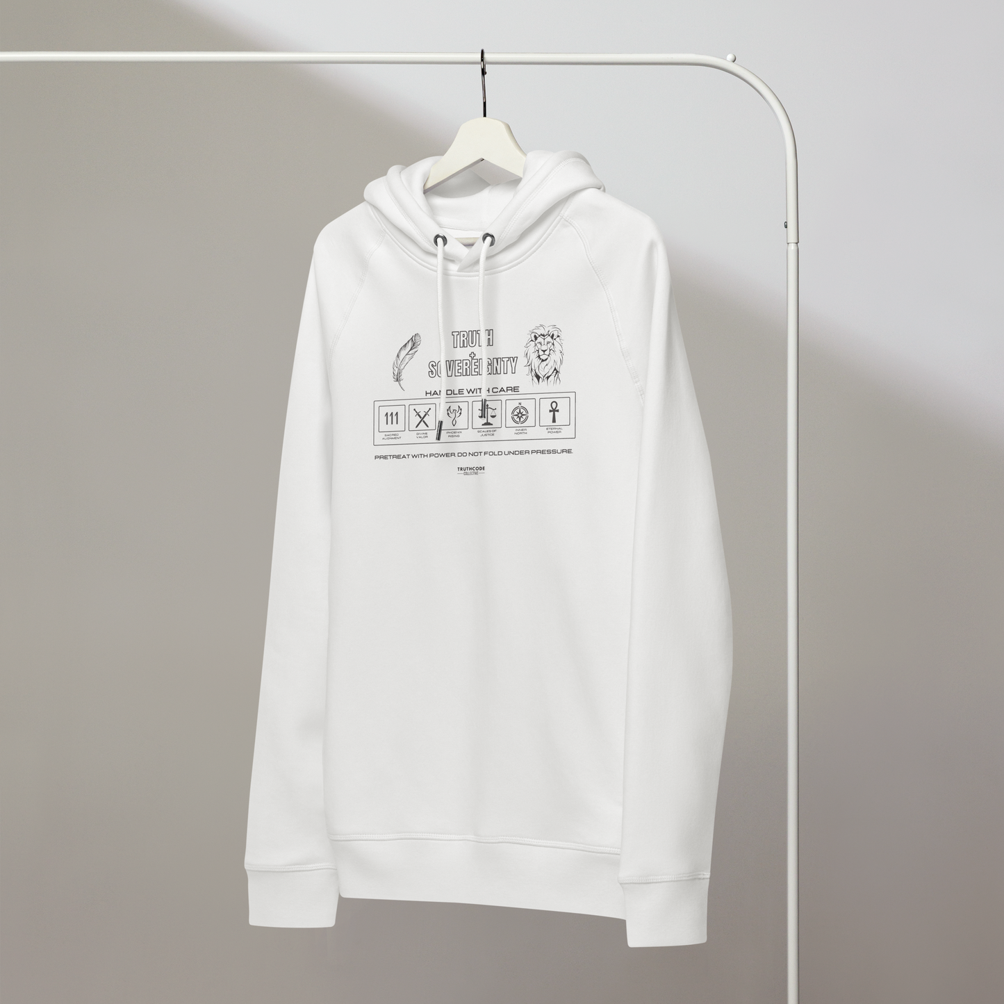White organic hoodie with text 'Truth + Sovereignty' with symbols graphics relating to it on a white hanger with a gray wall background