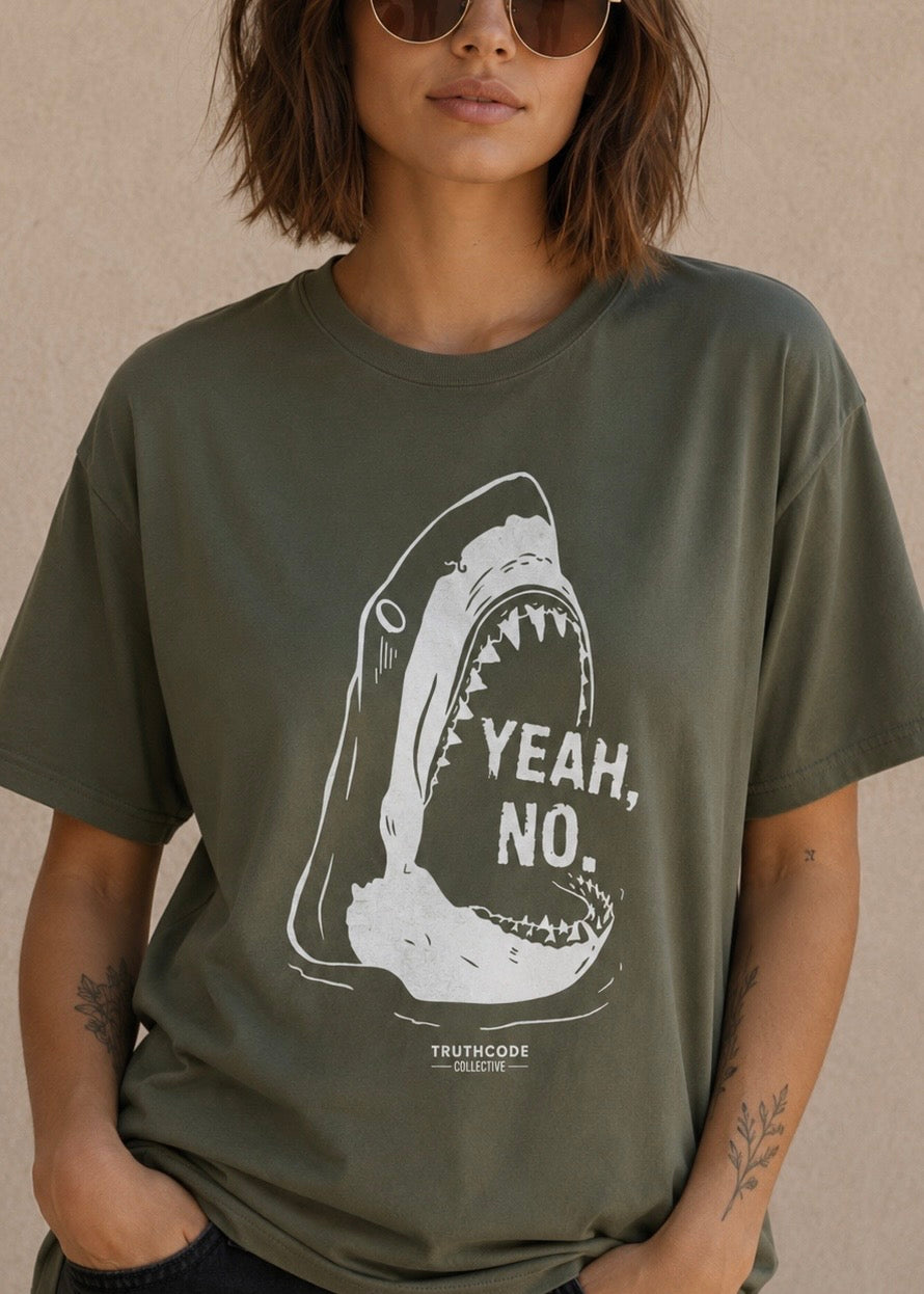 Person wearing a green t-shirt with a shark graphic and 'Yeah, No' text on a beige background