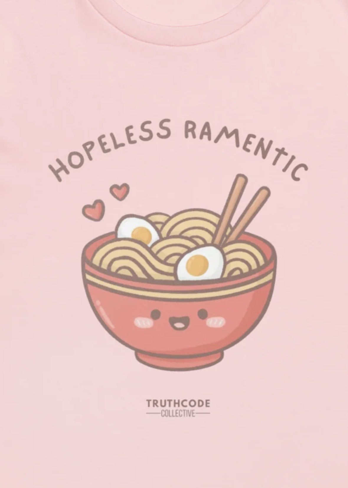 Close view of pink t-shirt with a bowl of ramen, chopsticks, and text 'Hopeless Ramentic' 