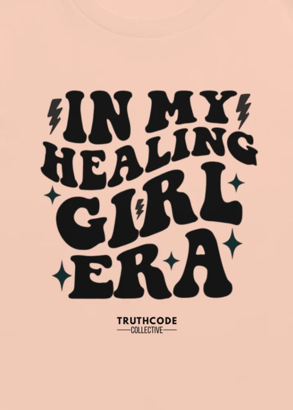 Close view of peach tee with text design 'IN MY HEALING GIRL ERA' 
