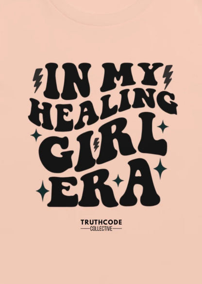 Close view of peach tee with text design 'IN MY HEALING GIRL ERA' 