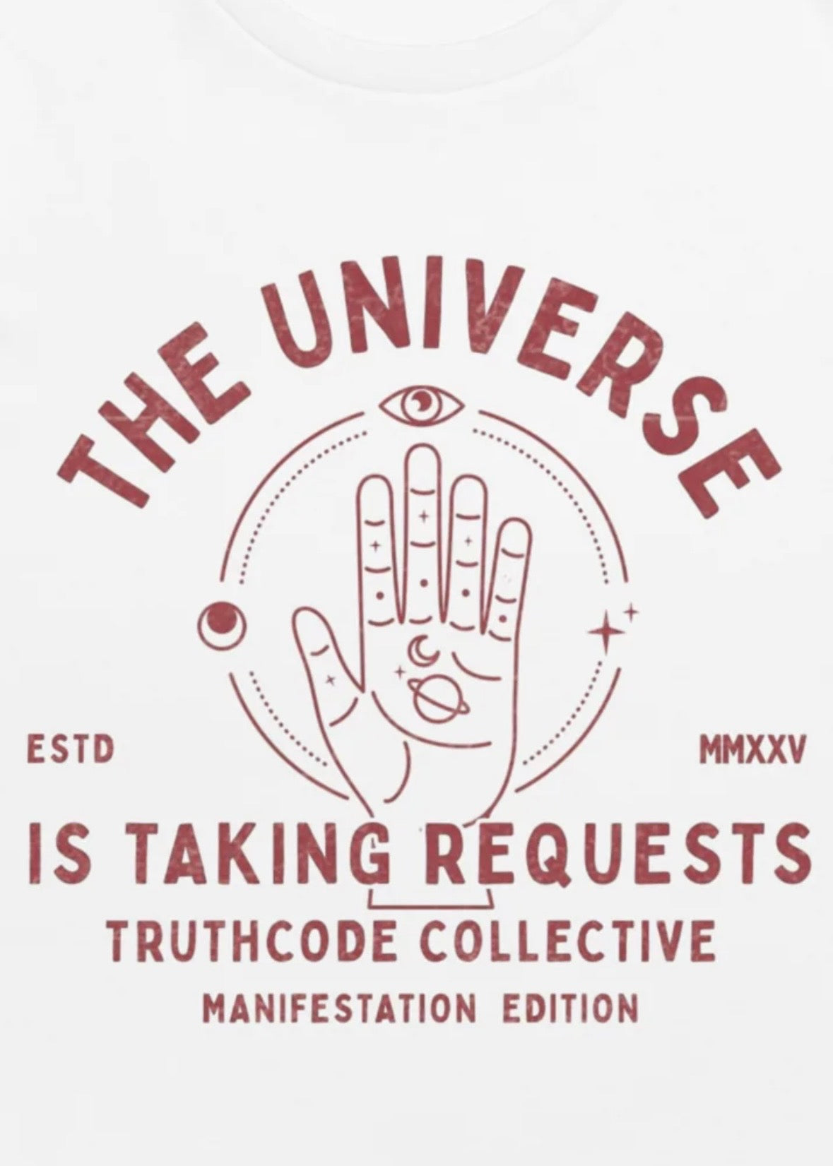 Close view of white organic t-shirt with graphic of a hand with symbols and text 'The universe is taking requests' against a white background