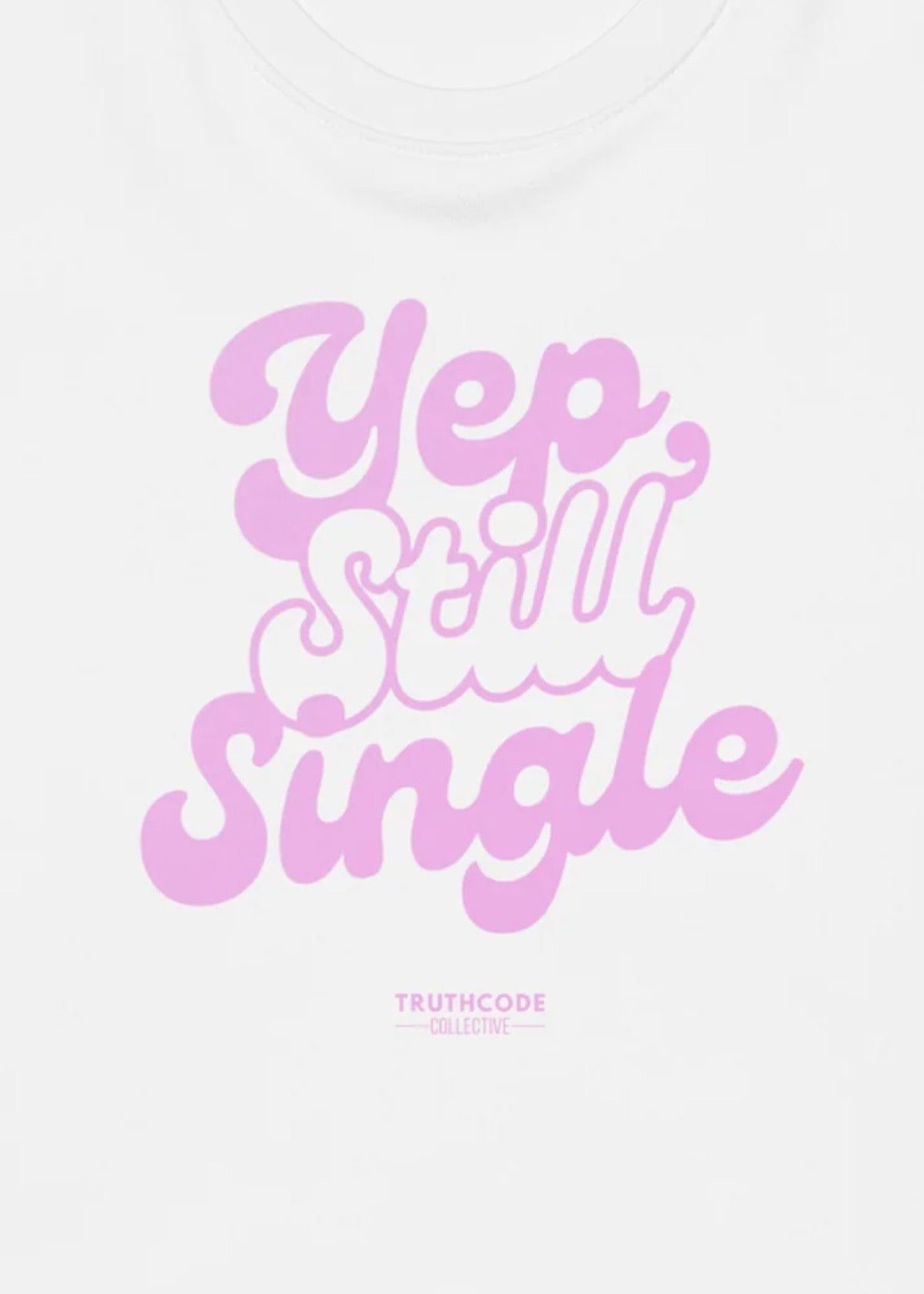 Close view of white t-shirt with pink text design 'Yep, Still Single' 