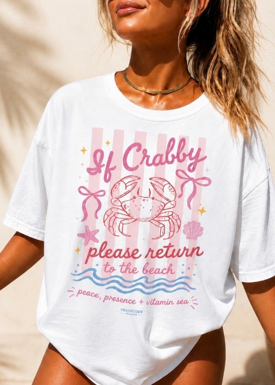 White t-shirt with a pink crab graphic and text on a beach setting. Text says 'if crabby please return to the beach'.