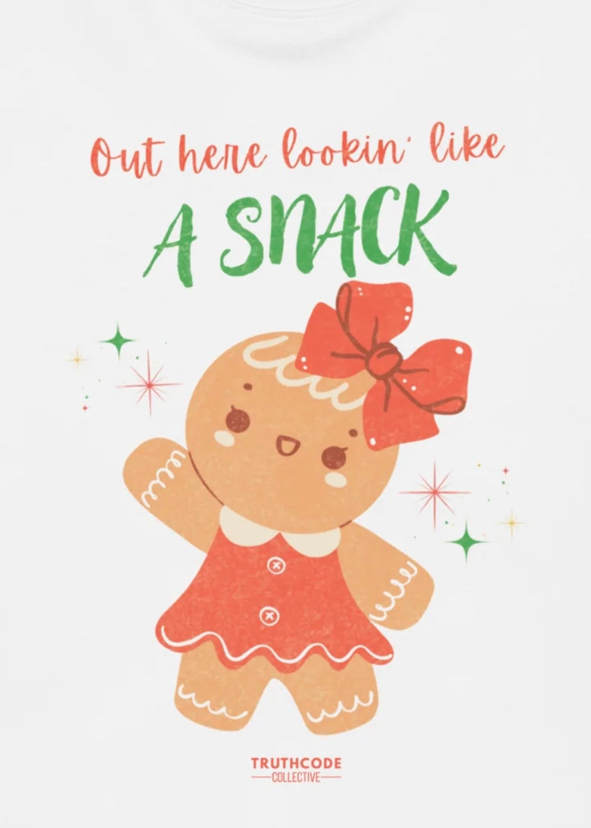 Close view of a white t-shirt with a graphic design of a gingerbread girl with text 'Out here lookin' like a snack' 