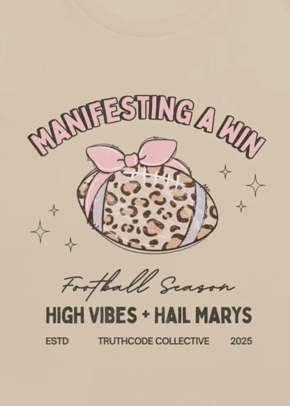 Close view of girly football graphic with a pink bow and text 'Manifesting a win, football season' and 'High vibes and hail marys' 