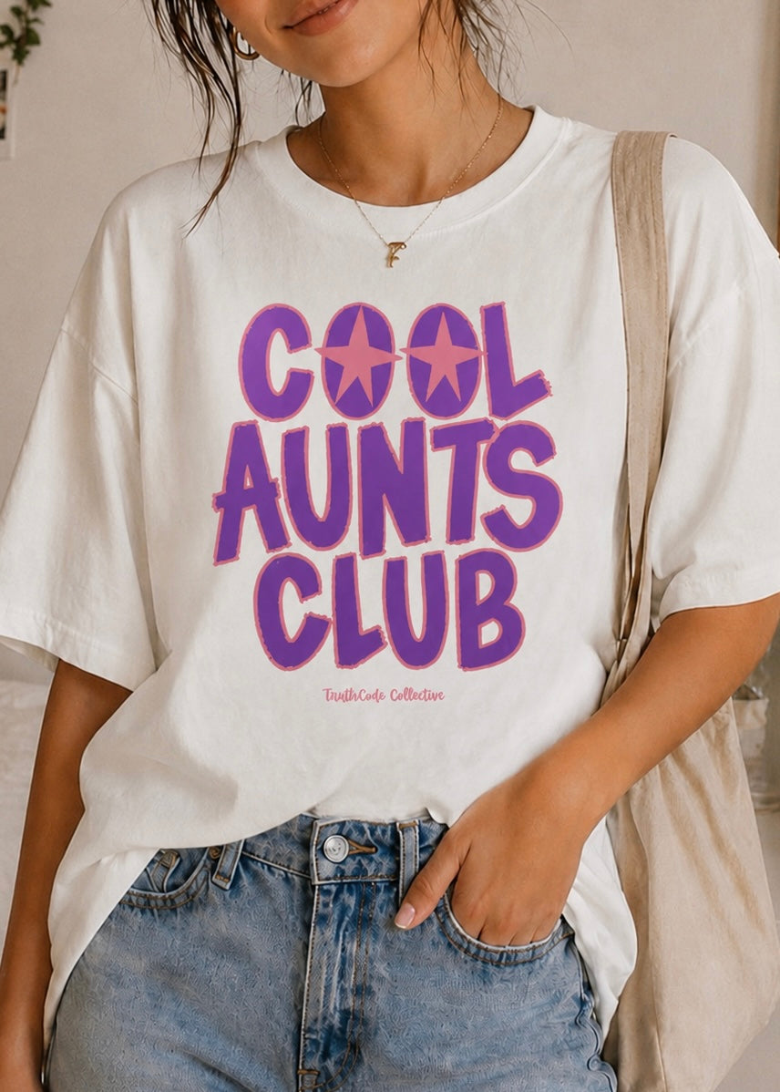Person wearing a white t-shirt with 'Cool Aunts Club' text in purple and pink.