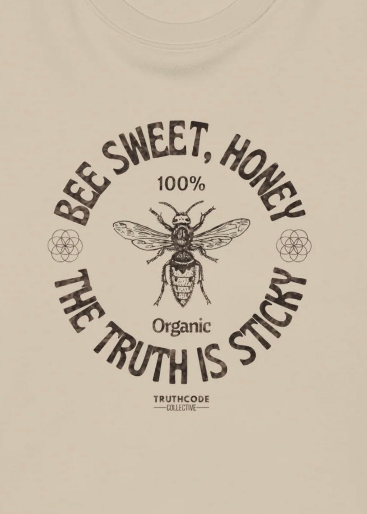 Close view of beige sweatshirt with a bee graphic and text 'Bee sweet, honey. The truth is sticky'