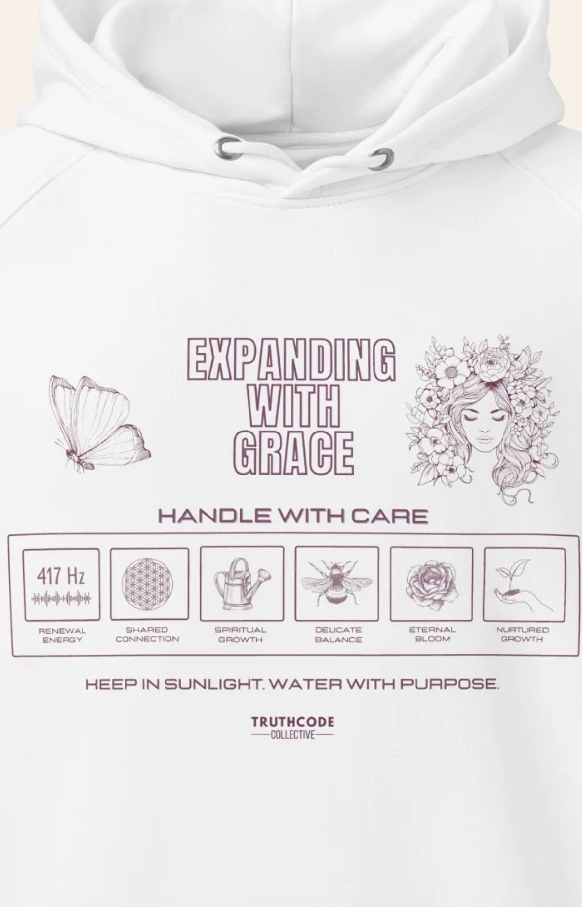 Close view of white hoodie with text 'Expanding with grace' and symbols relating to expansion in a laundry tag inspired design