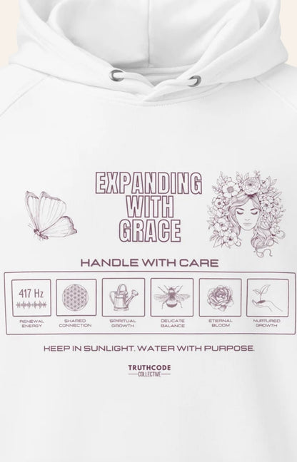 Close view of white hoodie with text 'Expanding with grace' and symbols relating to expansion in a laundry tag inspired design