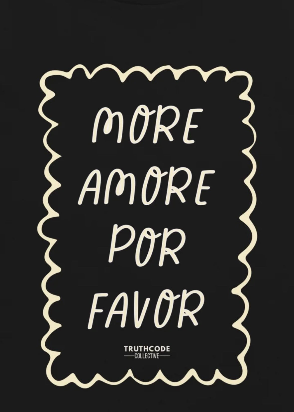 Close view of black t-shirt with white text 'MORE AMORE POR FAVOR' and 'TRUTHCODE COLLECTIVE' logo.