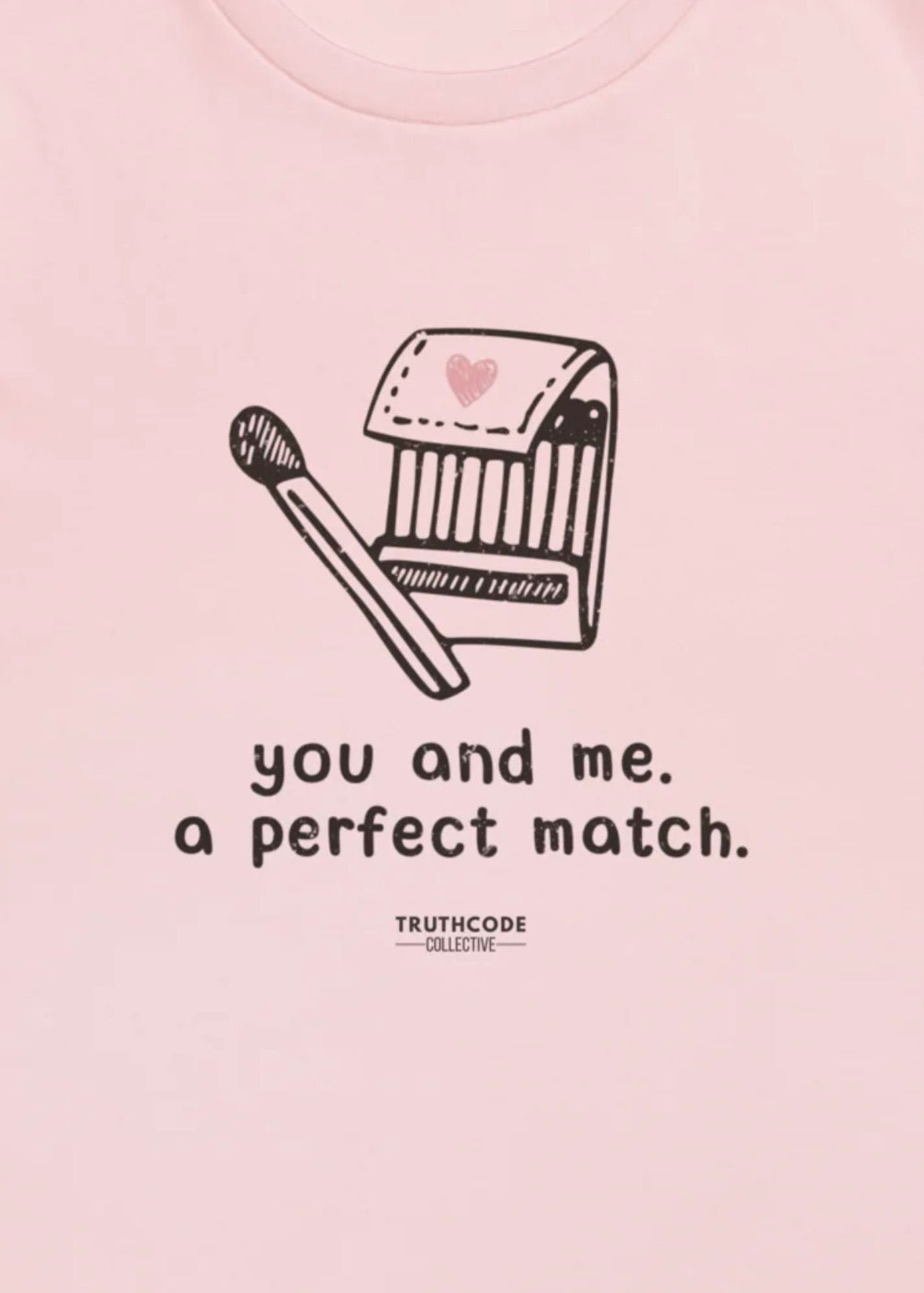 Close view of pink t-shirt and  graphic of a matchbox and matchstick with text 'you and me, a perfect match.' 