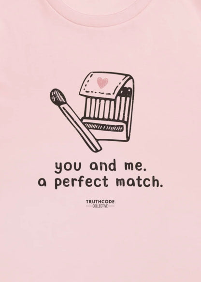 Close view of pink t-shirt and  graphic of a matchbox and matchstick with text 'you and me, a perfect match.' 