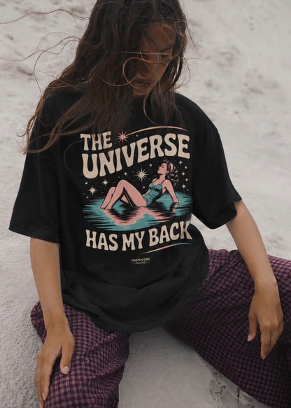 Person wearing a black t-shirt with 'The Universe Has My Back' graphic design.
