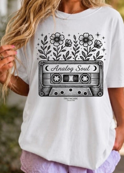 White t-shirt with a cassette tape graphic and floral design, worn by a person. Text says 'analog soul'.