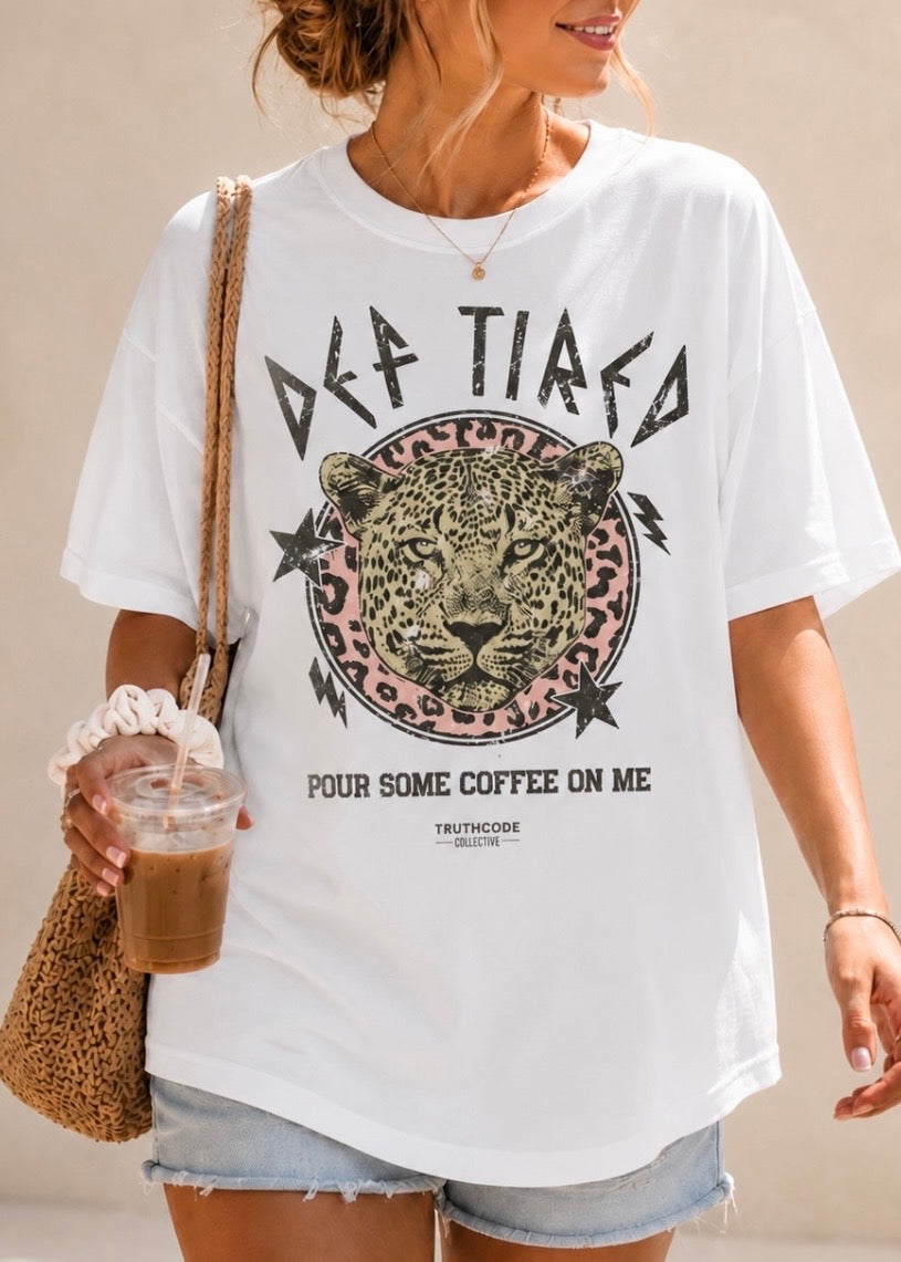 Person wearing a white t-shirt with a leopard graphic and text, holding a drink. Text says 'Def Tired', 'Pour Some Coffee On Me'. 