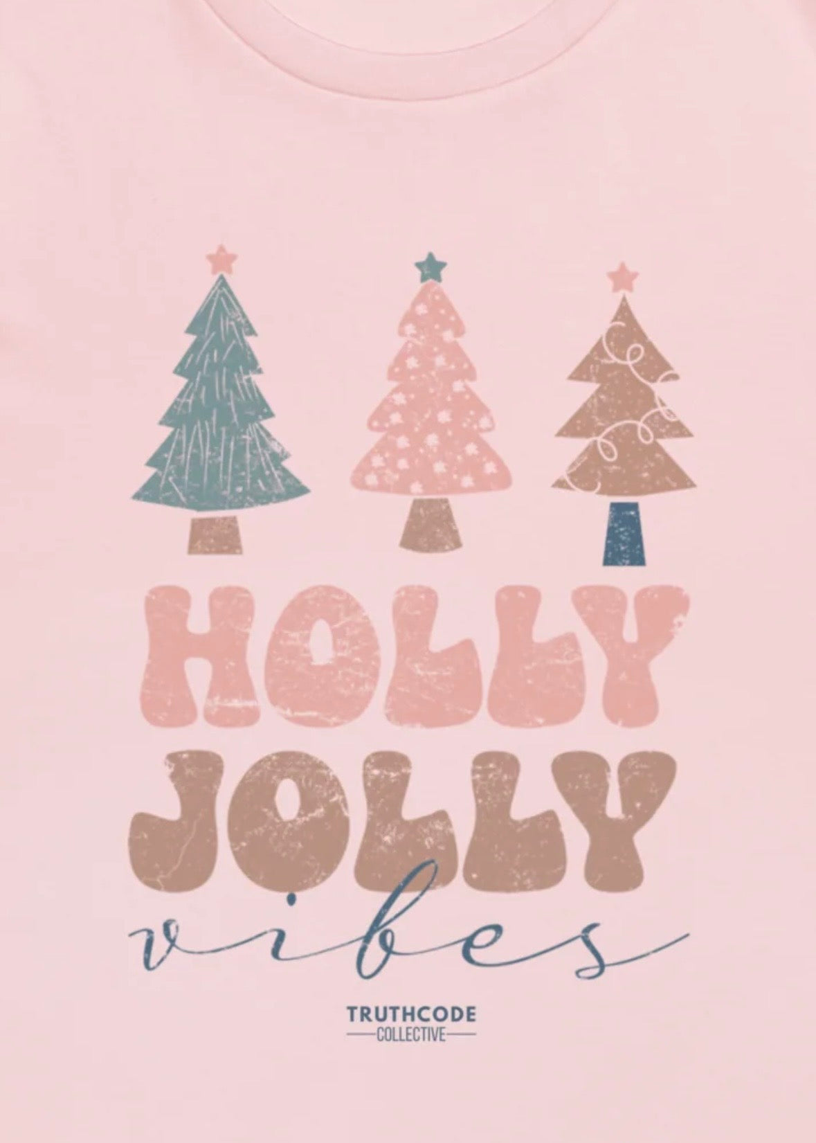 Close view of pink t-shirt with Christmas trees and 'Holly Jolly Vibes' text