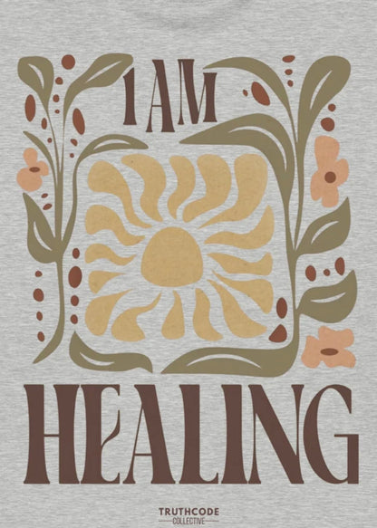 Close view of gray t-shirt with 'I AM HEALING' text and sun and plant design