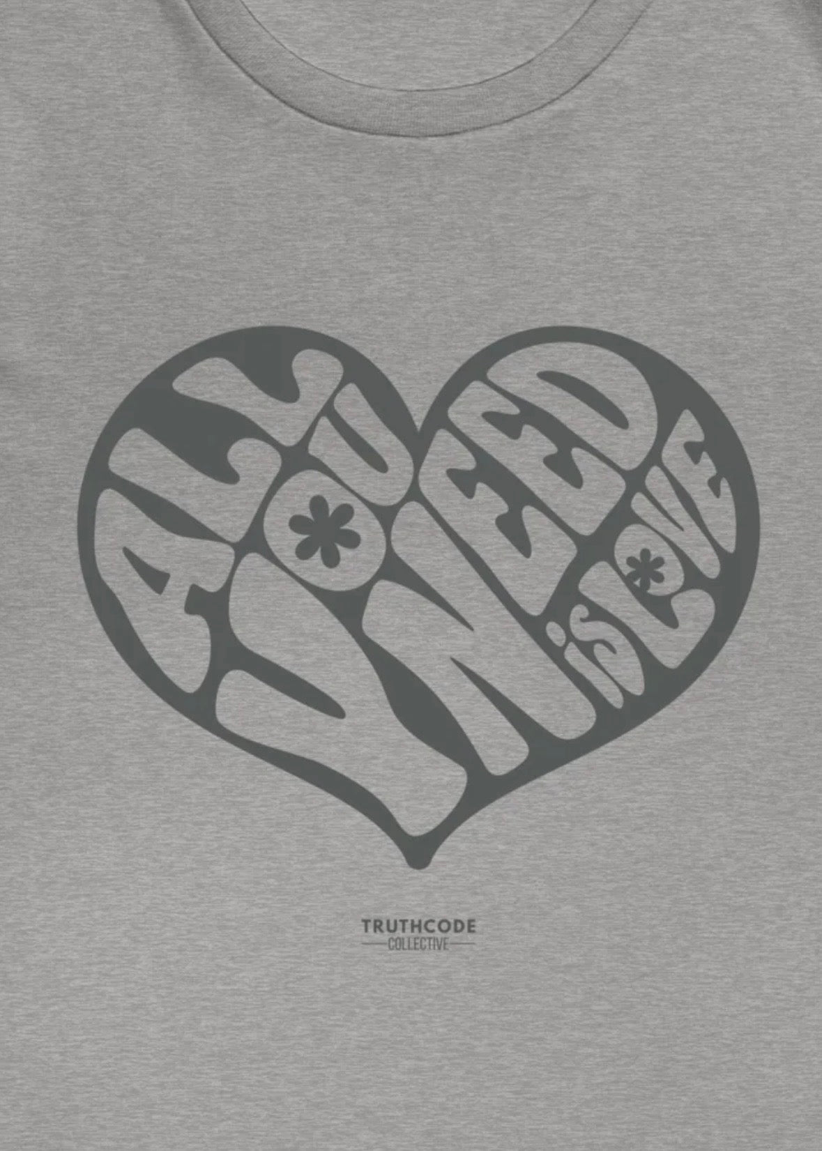 Close view of gray heart-shaped logo and text 'All you need is love', against a white background