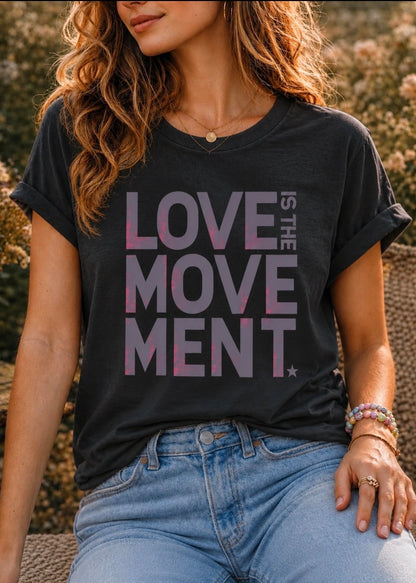 A woman wearing a black graphic t-shirt with the text 'LOVE THE MOVE MENT' in a pink-to-purple gradient, paired with light blue jeans.