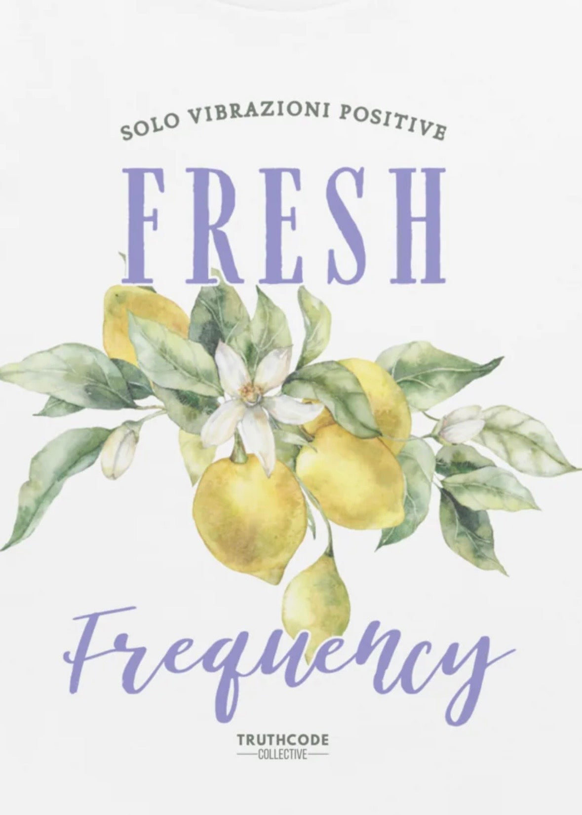 Close view of white t-shirt with graphic design of decorative  lemons, leaves, and text 'Fresh Frequency' 