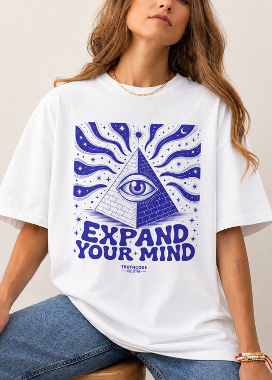 Person wearing a white t-shirt with a blue pyramid and eye design, text 'EXPAND YOUR MIND' on a plain background
