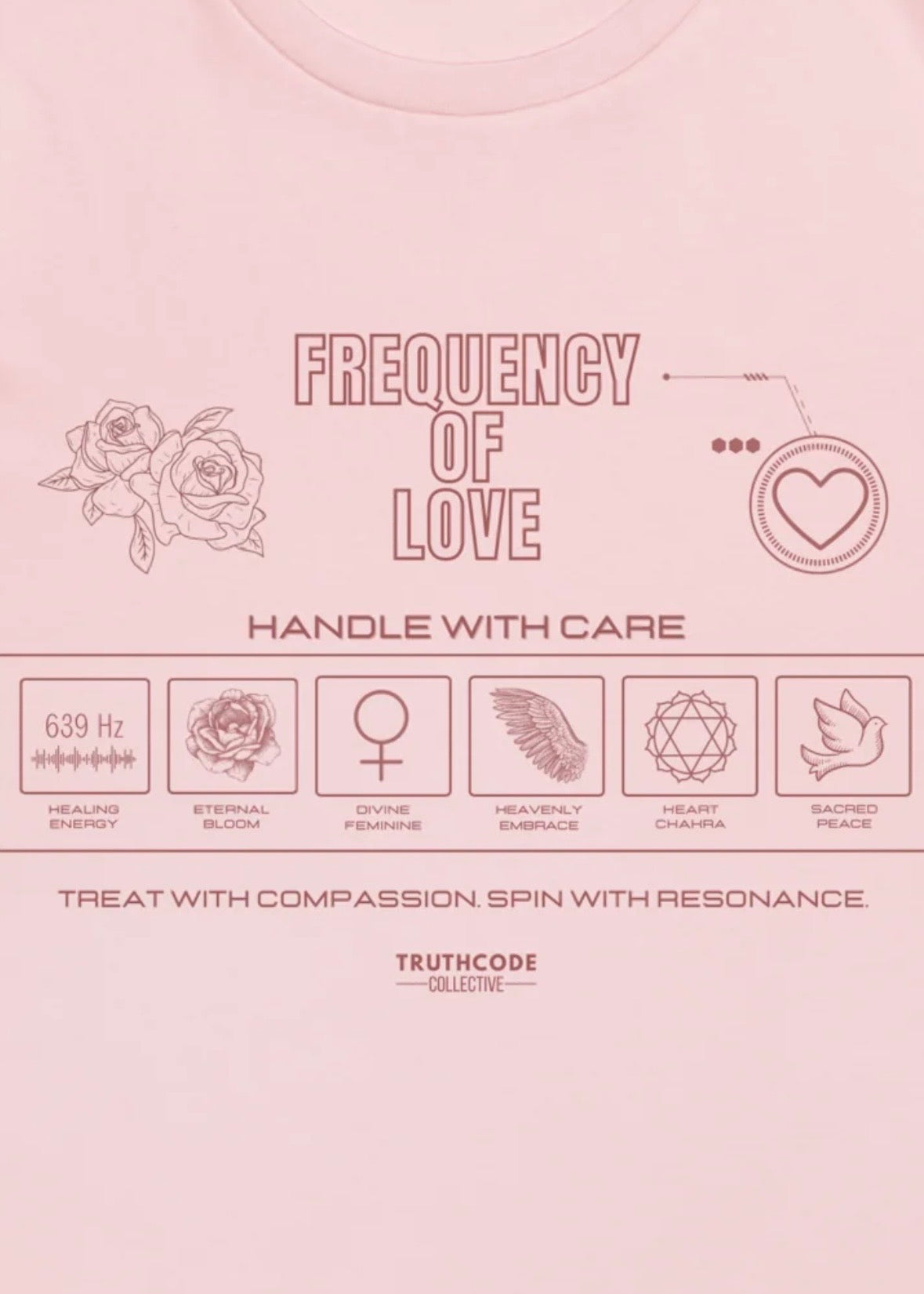Close view of pink organic t-shirt with 'Frequency of Love' text and various symbols relating to love in a laundry tag style graphic design.