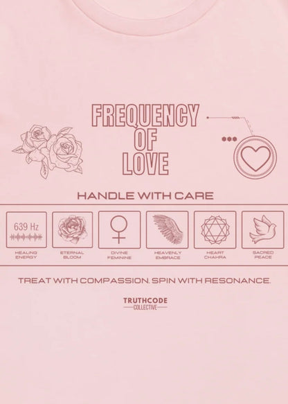 Close view of pink organic t-shirt with 'Frequency of Love' text and various symbols relating to love in a laundry tag style graphic design.