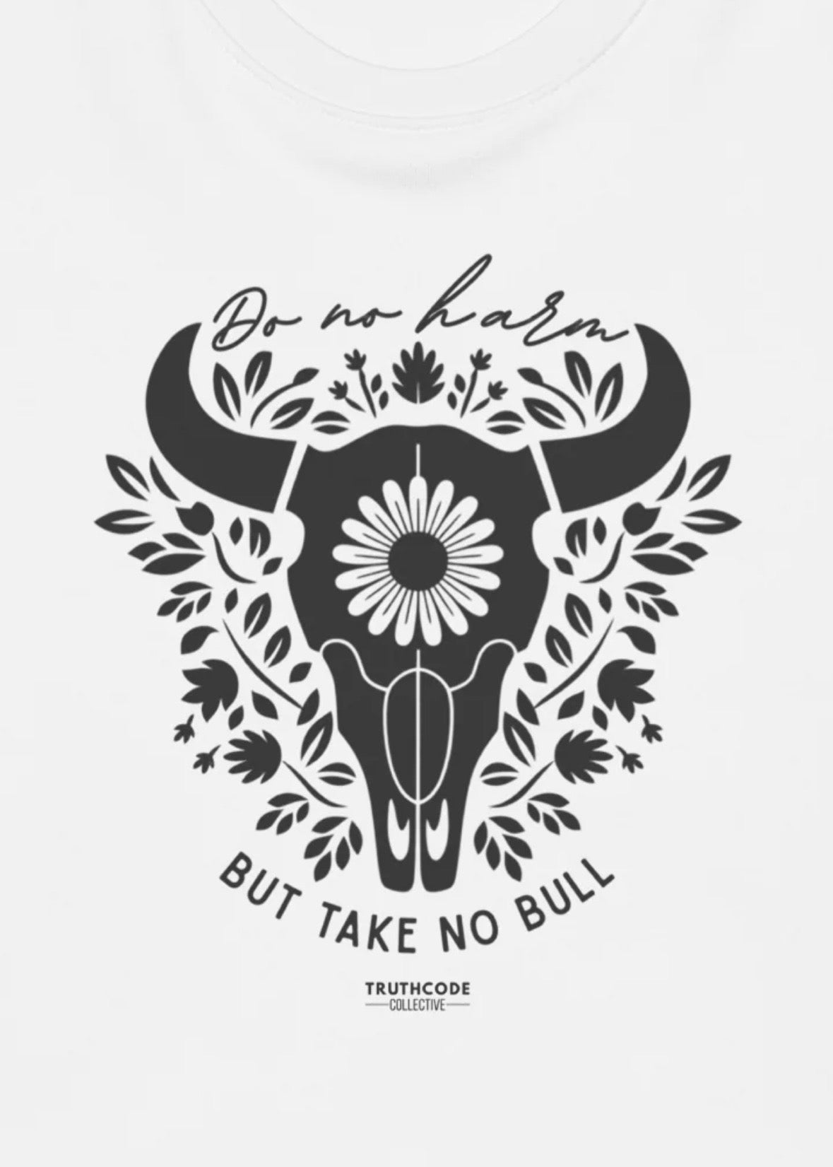 Close view of white t-shirt with black bull skull design with floral elements and text 'Do no harm, but take no bull' 