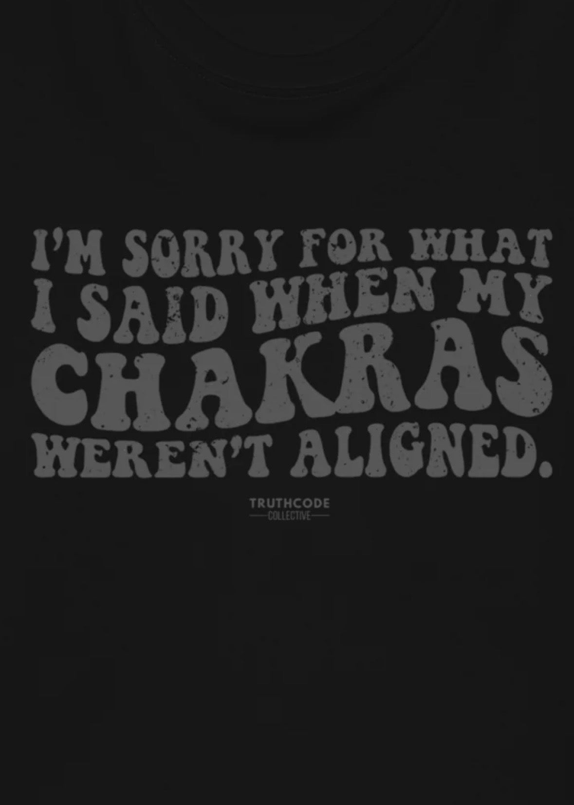 Close view of black t-shirt with text design 'I'm sorry for what I said when my chakras weren't aligned' 