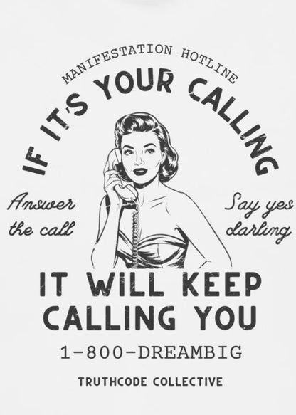 Close view of a white t-shirt with vintage-style graphic design of a woman on a phone and text 'If it's your calling, it will keep calling you 1-800-DREAMBIG'