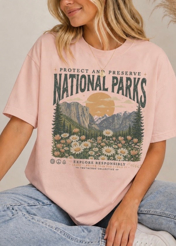 Person wearing a pink t-shirt with a 'National Parks' graphic design. Text says 'protect and preserve, explore responsibly'.