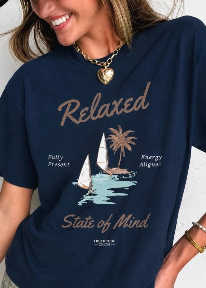 Person wearing a navy blue t-shirt with a graphic and text, standing against a neutral background. Text says 'relaxed state of mind', 'fully present' and 'energy aligned'.