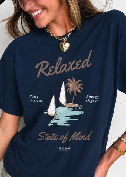 Person wearing a navy blue t-shirt with a graphic and text, standing against a neutral background. Text says 'relaxed state of mind', 'fully present' and 'energy aligned'.