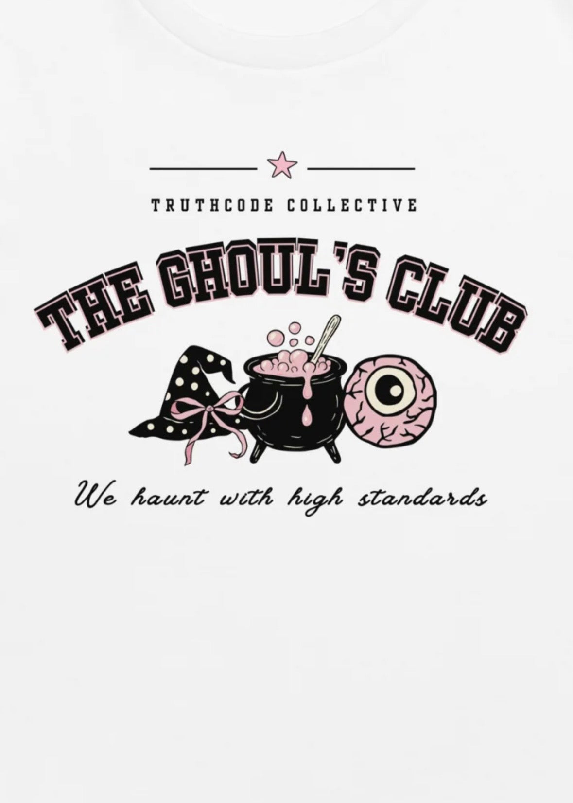 Close view of white t-shirt with text 'The Ghoul's Club, we haunt with high standards' with a witch hat, cauldron, and eye design