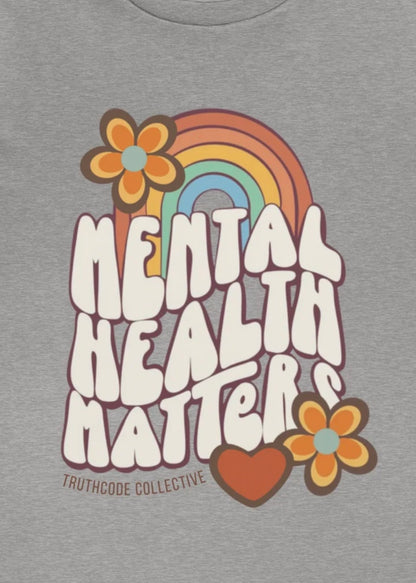 Close view of gray t-shirt with 'Mental Health Matters' graphic design featuring a rainbow, flowers, and heart 
