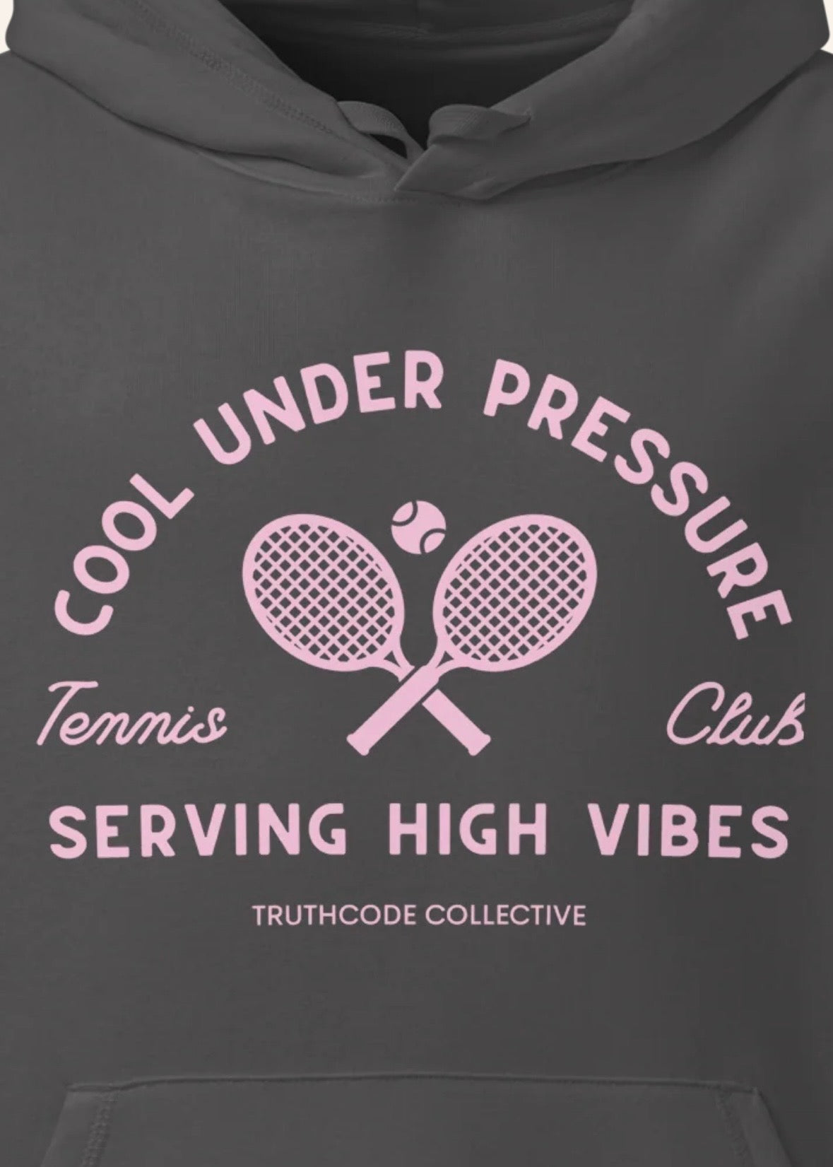 Close view of dark gray organic hoodie with pink and white text 'Cool under pressure, serving high vibes' and tennis graphics on a white background