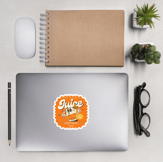 Aerial view of a desktop with laptop showing a sticker with a cartoon juice glass graphic and text 'Juice, fresh downloads, organic ingredients fortified with lightcodes'