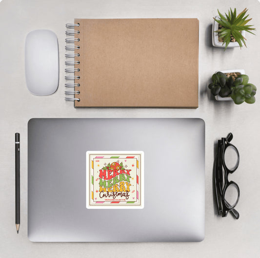 Laptop with a 'Merry Merry Christmas' sticker and other desktop accessories around