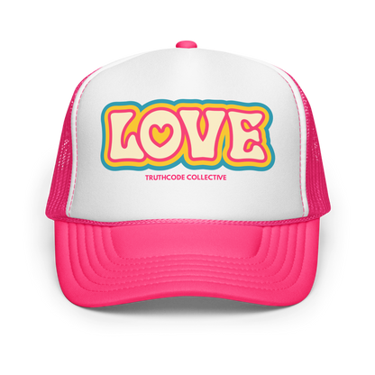 Pink and white trucker hat with 'LOVE' text and 'Truthcode Collective' logo on a white background