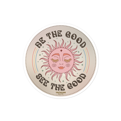 Circular sticker with sun design and text 'Be the good, see the good' on a beige background